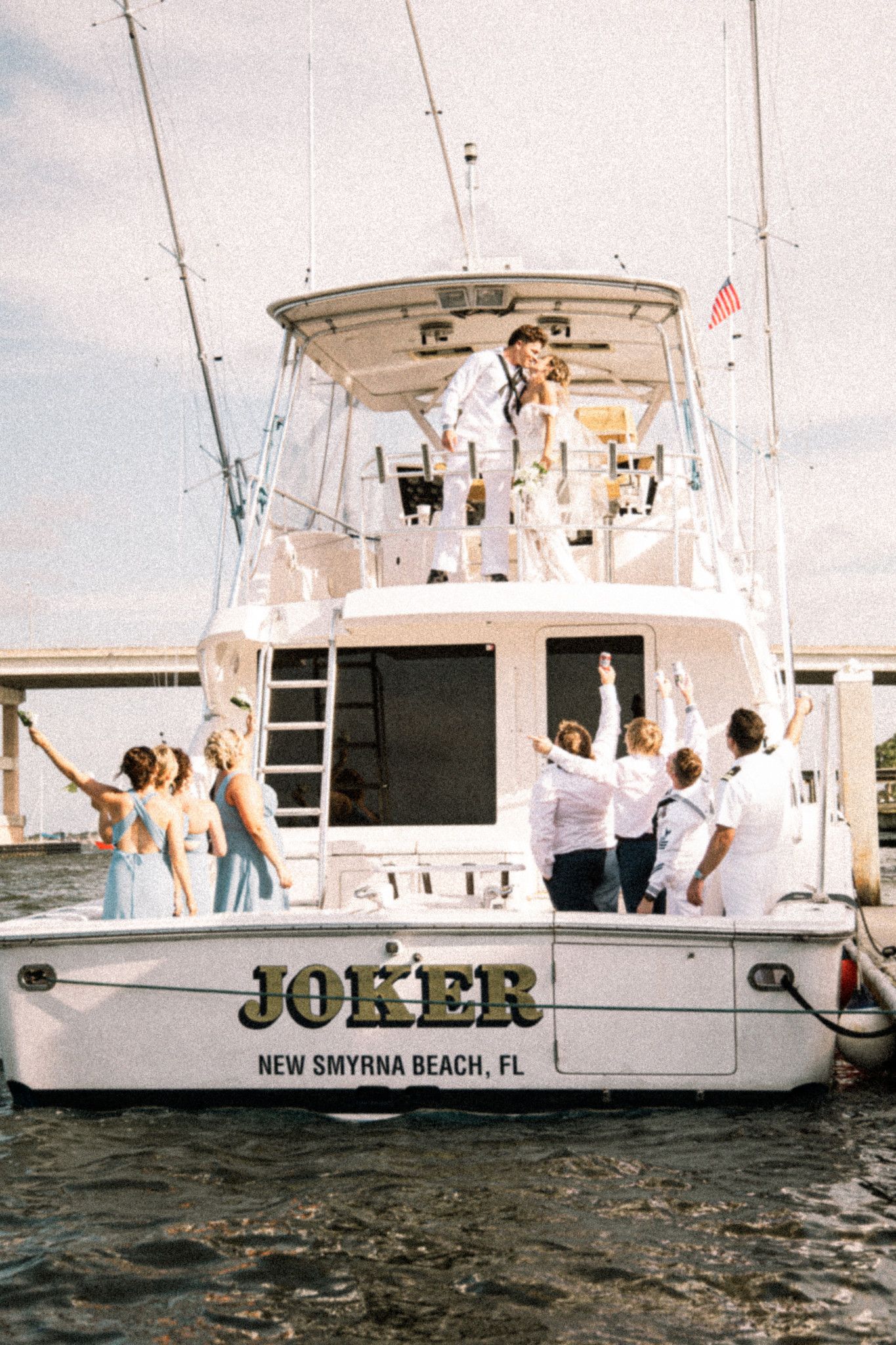 Wedding party celebrating on the stern of a white sport fishing boat named Joker from New Smyrna Beach FL.