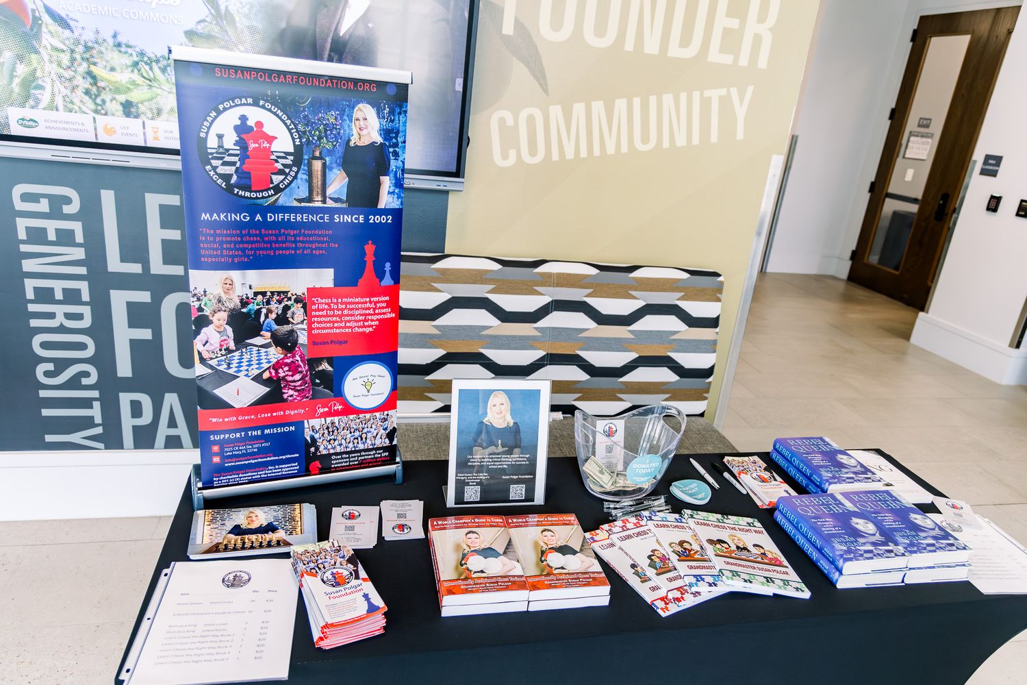 A nonprofit organization display table with banners, brochures, and promotional materials in a community event space.