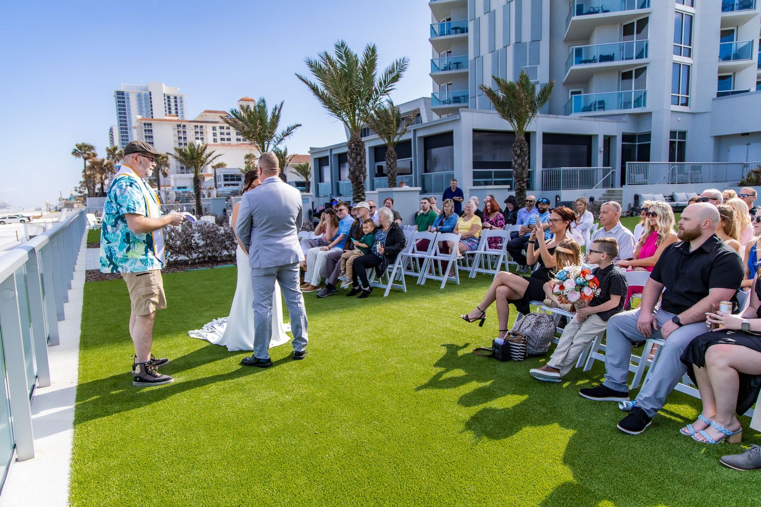Outdoor wedding ceremony setup on a rooftop terrace with artificial grass and ocean views in the background.