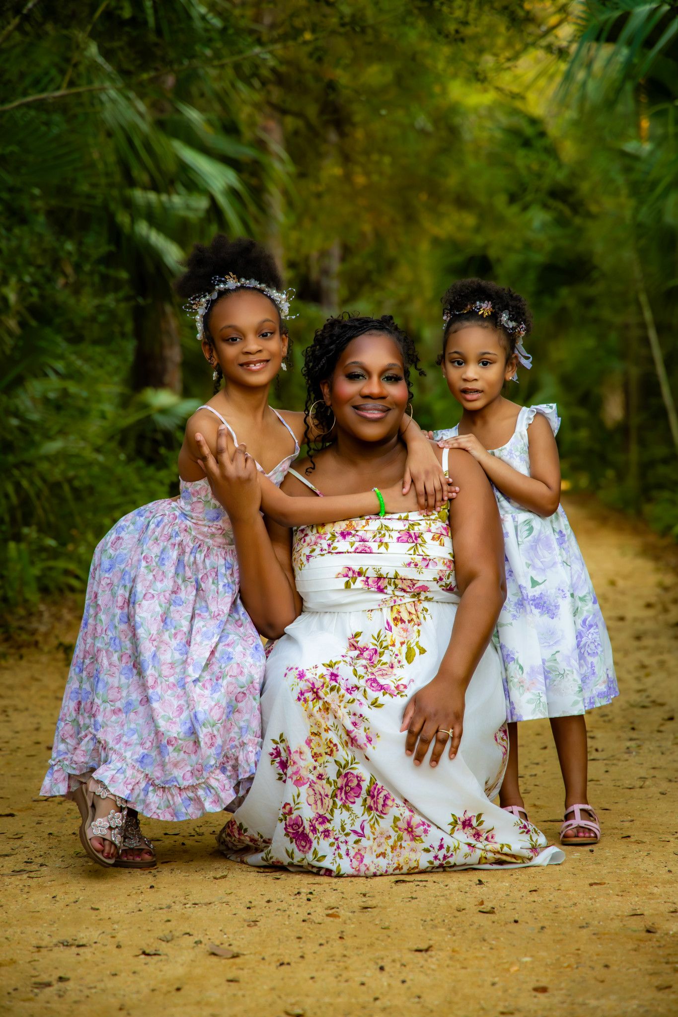A loving family portrait series shows tender moments between mother and daughters in a natural outdoor setting.
