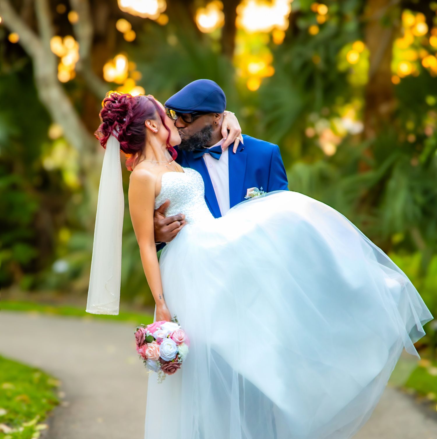 Romantic wedding couple embraces in a dip pose during sunset in a lush garden setting.