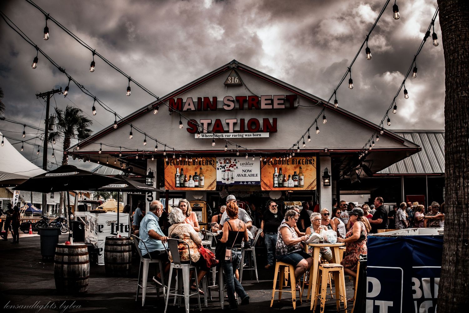 Outdoor bar patio with string lights and cloudy dramatic sky overhead.