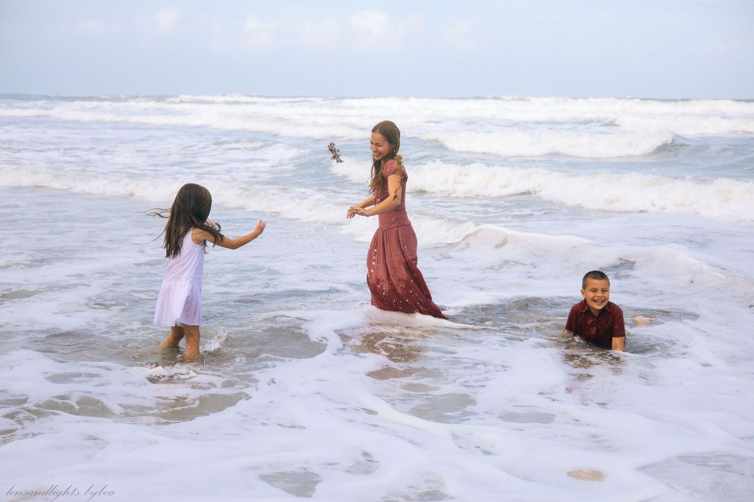 Group of people playing and splashing in ocean waves at the beach during daytime.