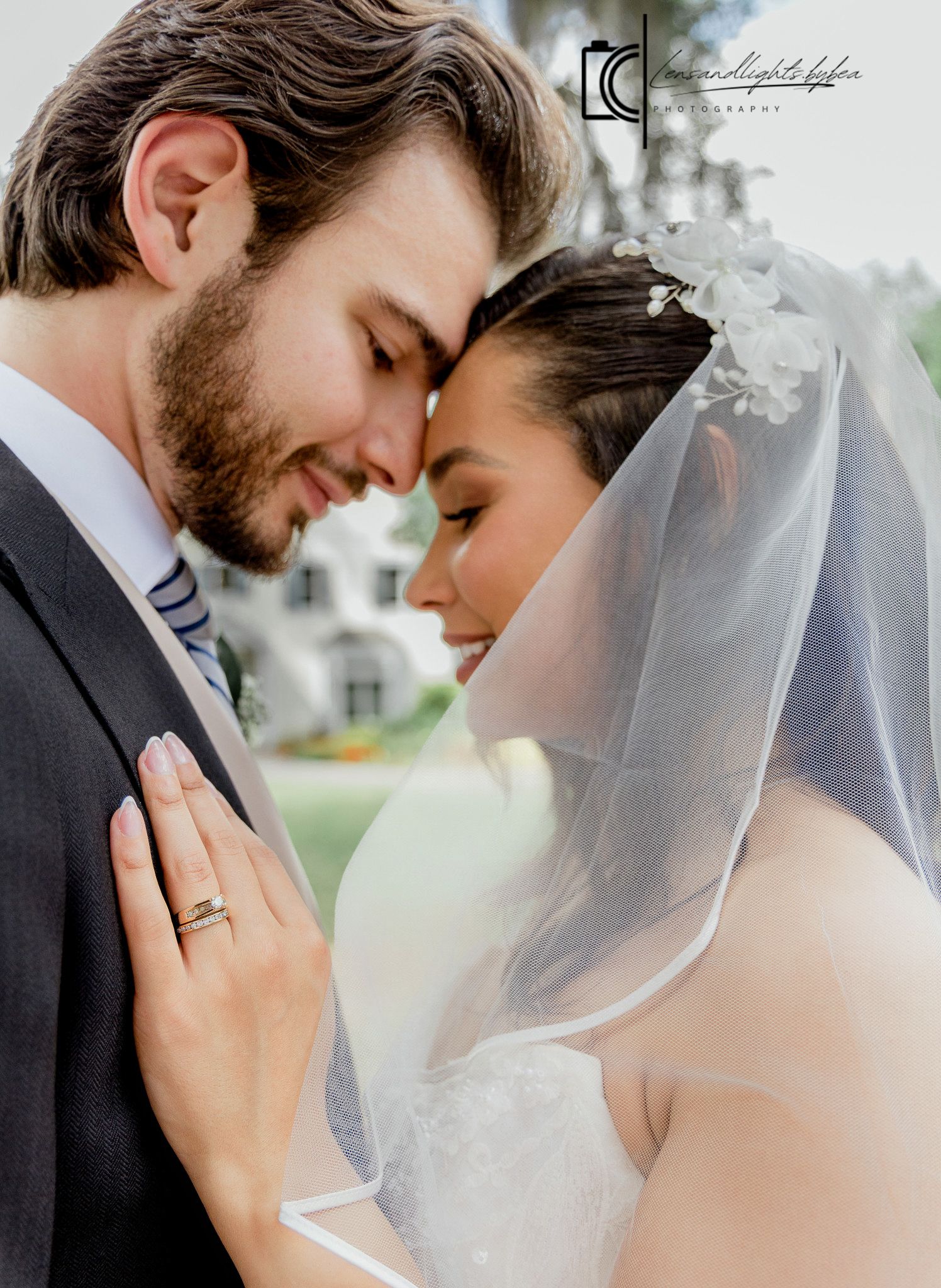 Bride and groom touching foreheads tenderly in an intimate wedding portrait outdoors.