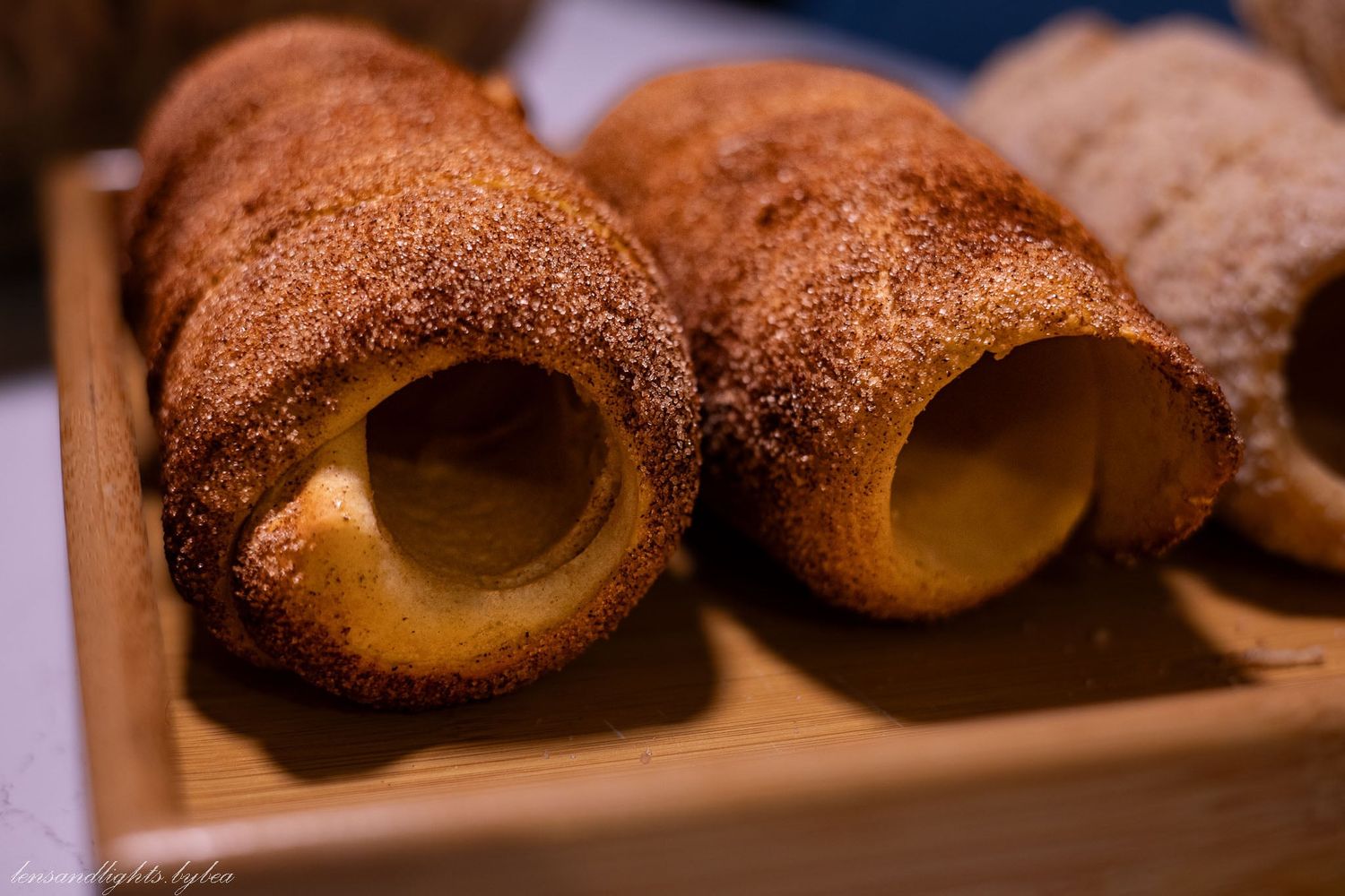 Close-up of chocolate-dusted pastry rolls filled with cream custard displayed on a wooden surface.