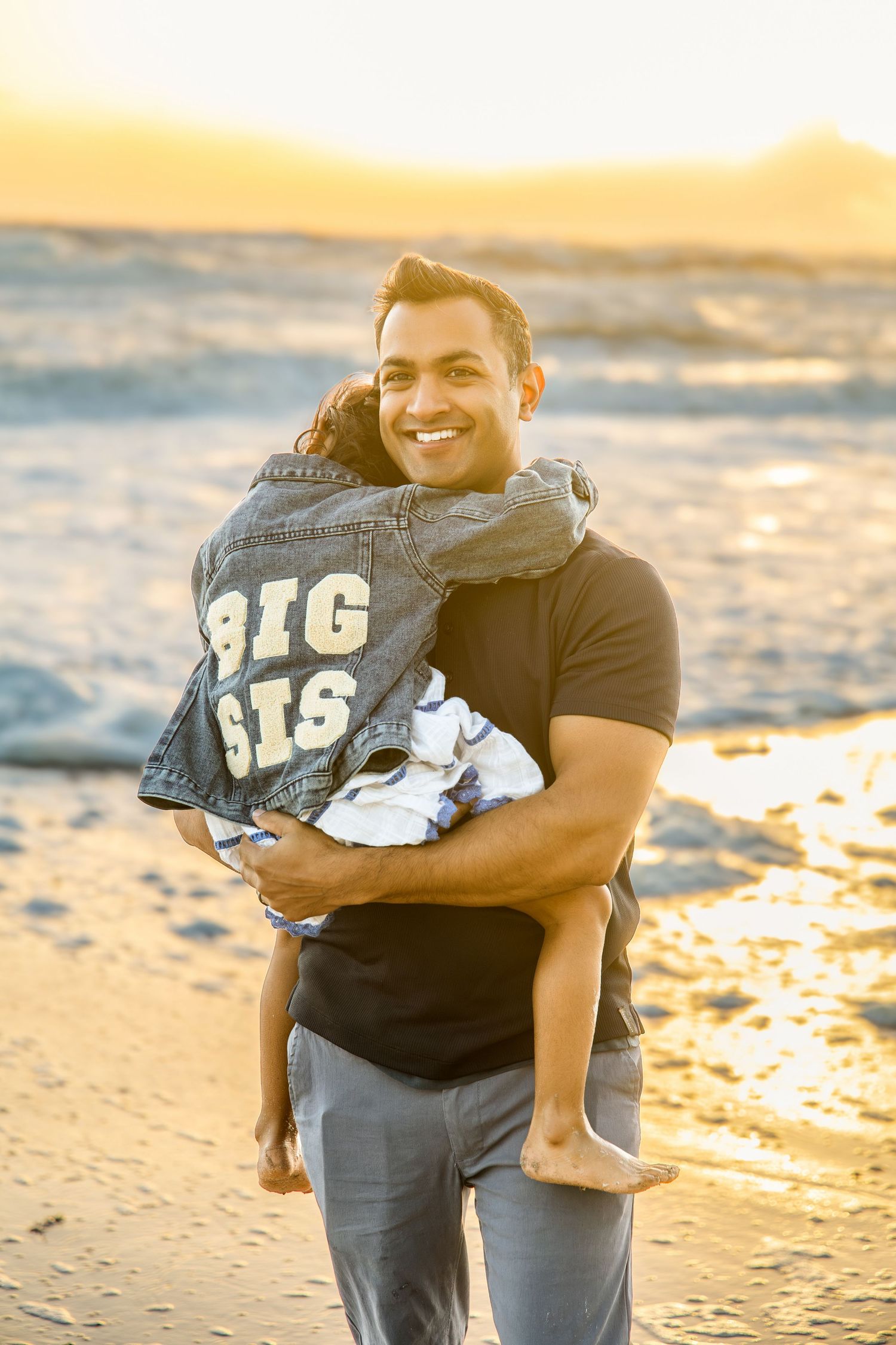Smiling man holding a child in a denim jacket reading 