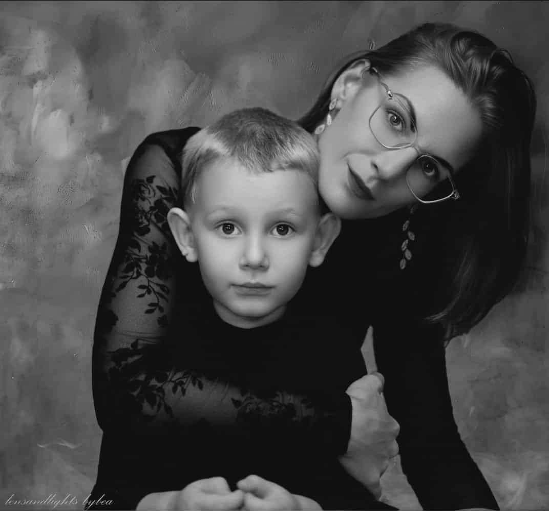 A black and white portrait showing a tender moment between parent and child.