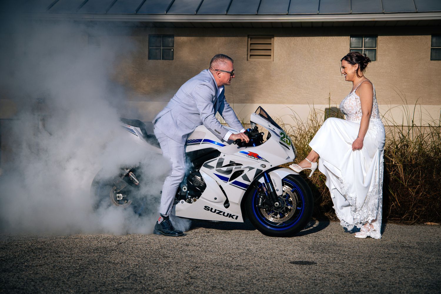 A creative motorcycle-themed wedding photo series showing a couple posing with a white sport bike in dramatic smoke.