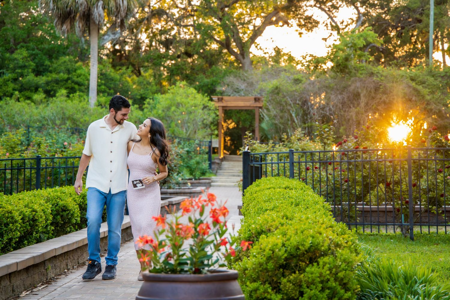 Couple sharing a romantic moment in a lush garden at golden hour, surrounded by vibrant flowers and greenery.
