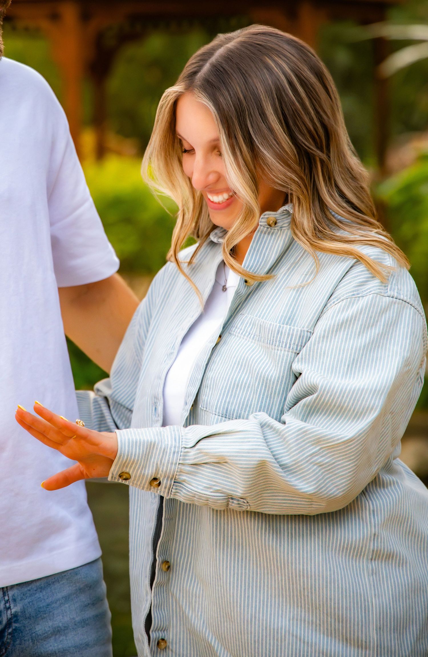 A series of photos showing someone wearing a light striped button-up shirt and white t-shirt in an outdoor setting.