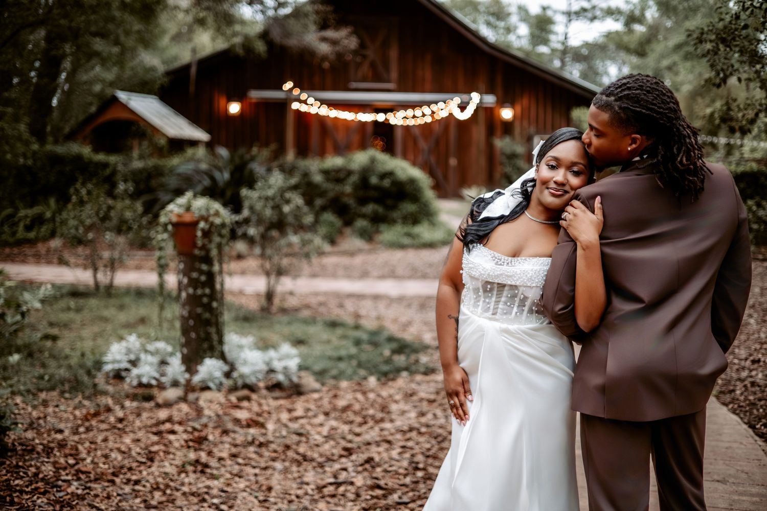 A couple shares a romantic embrace during their rustic barn wedding celebration.