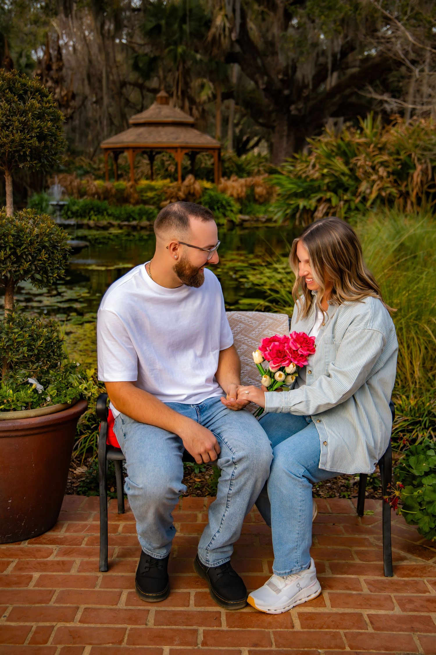 A couple sits together on a brick patio bench sharing tender moments in a garden setting.