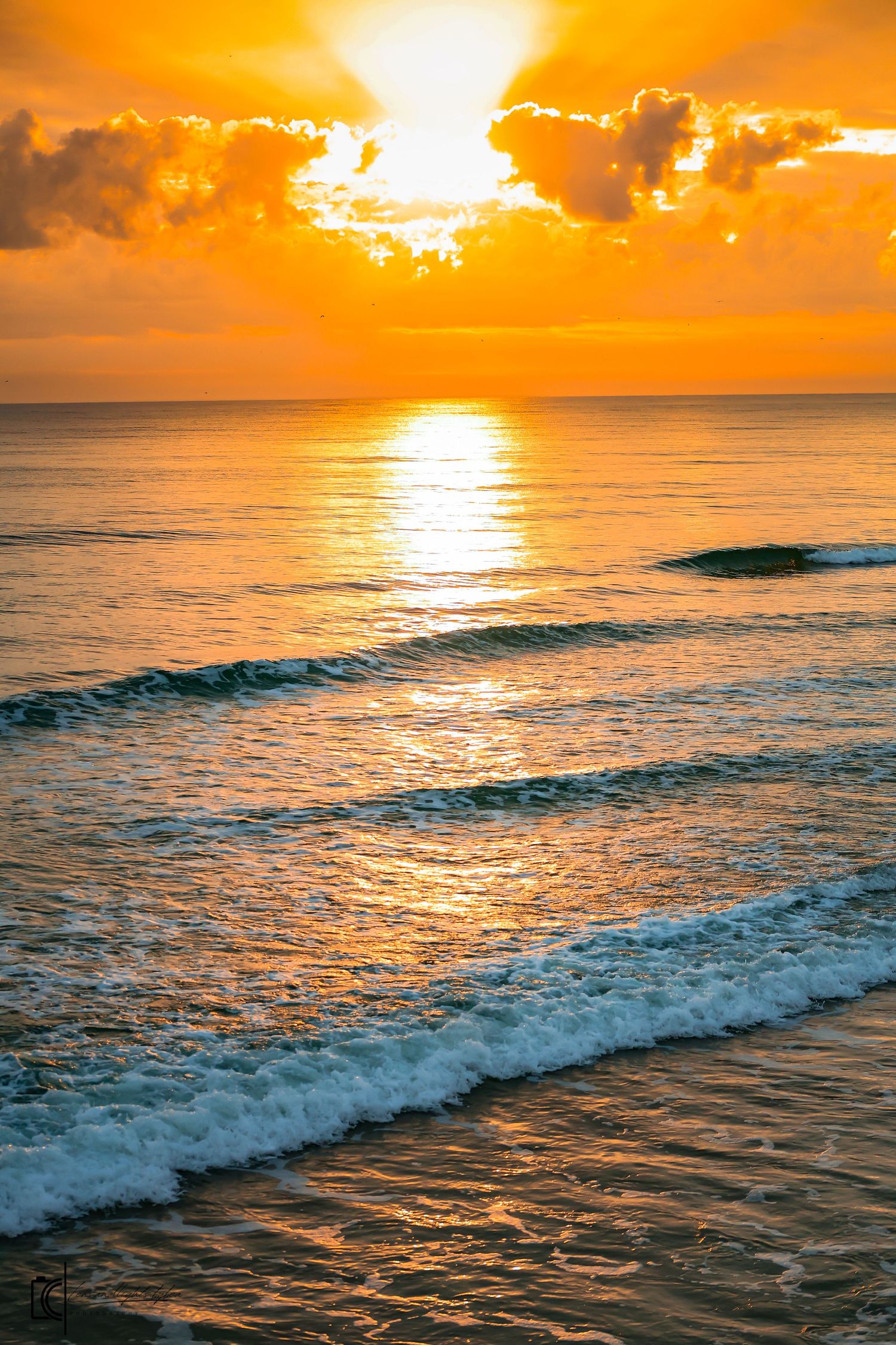 Dramatic orange sunset over ocean waves with golden light reflecting off rippling water and breaking surf at dusk.