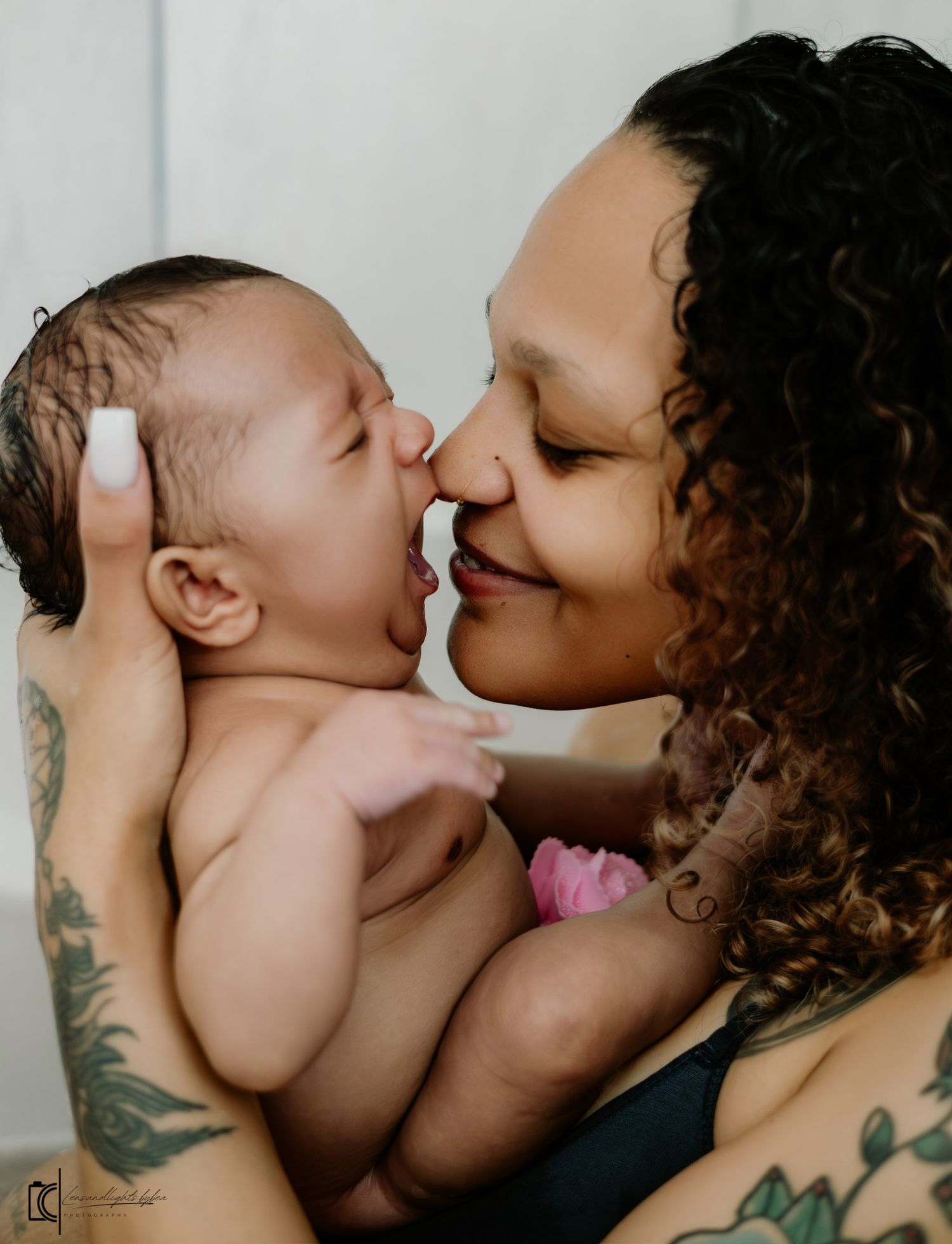 Tender moments captured in black and white showing parent with tattoos bonding with their infant child.