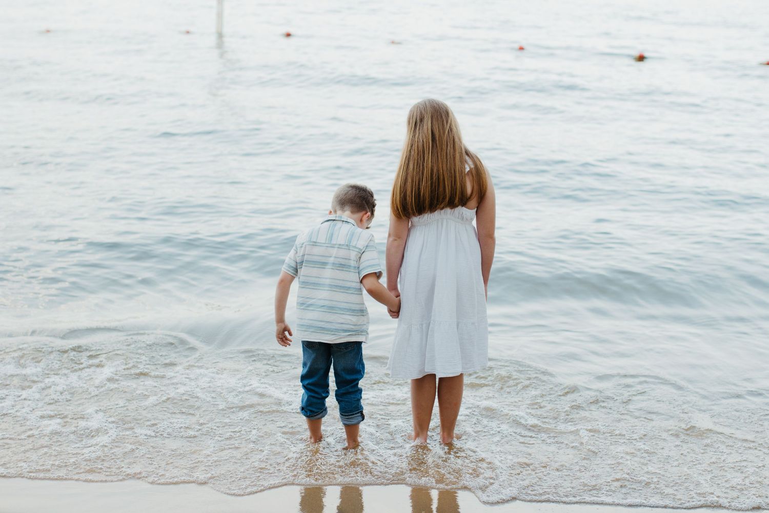 siblings holding hands outside during a family session