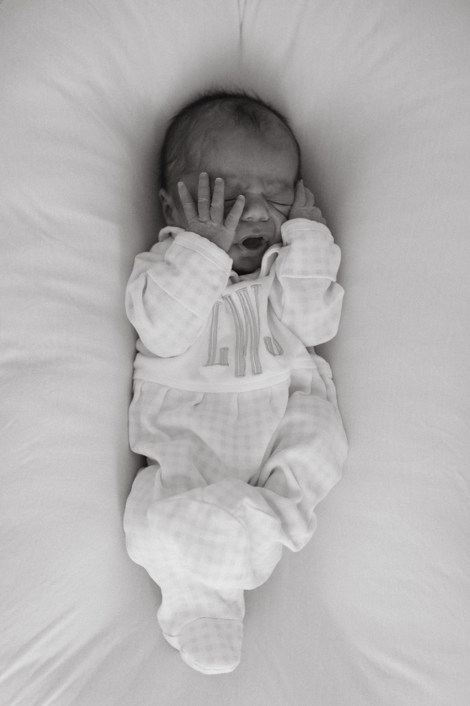 Newborn baby sleeping peacefully with hands covering their face