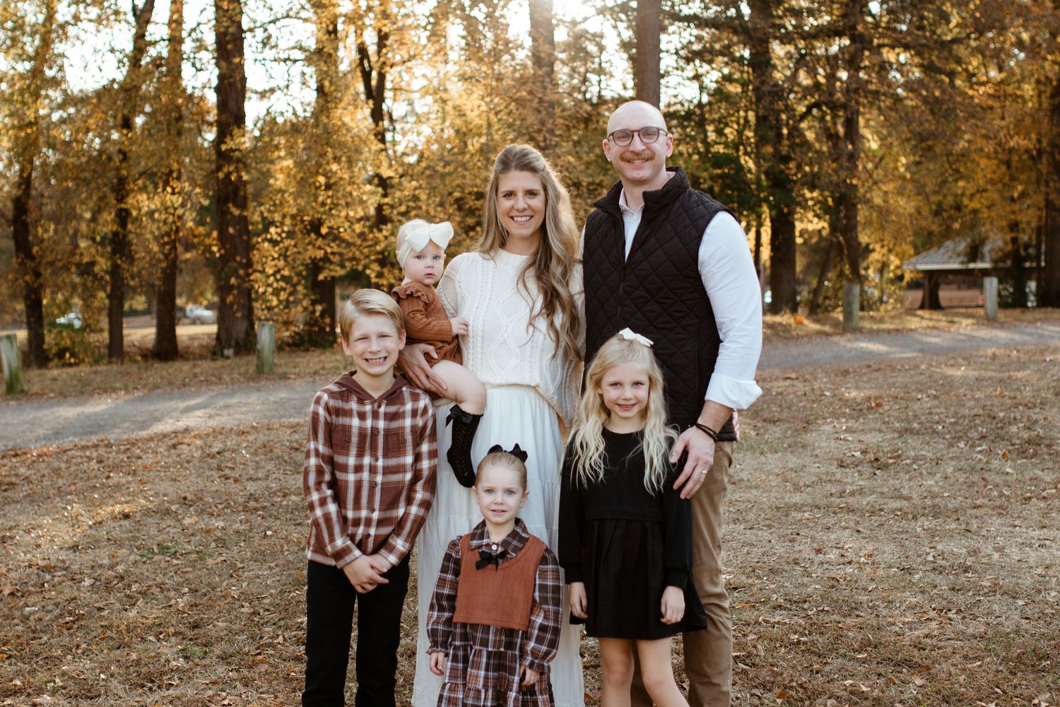 Rock Hill Family of six posing outdoors in autumn, wearing coordinated fall outfits among golden trees.