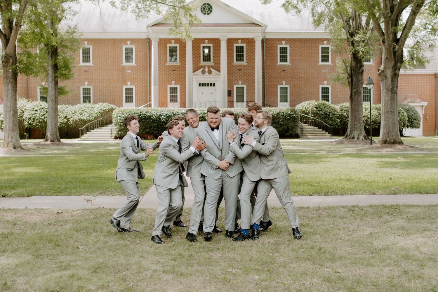 Groom posing with groomsmen outdoors on wedding day