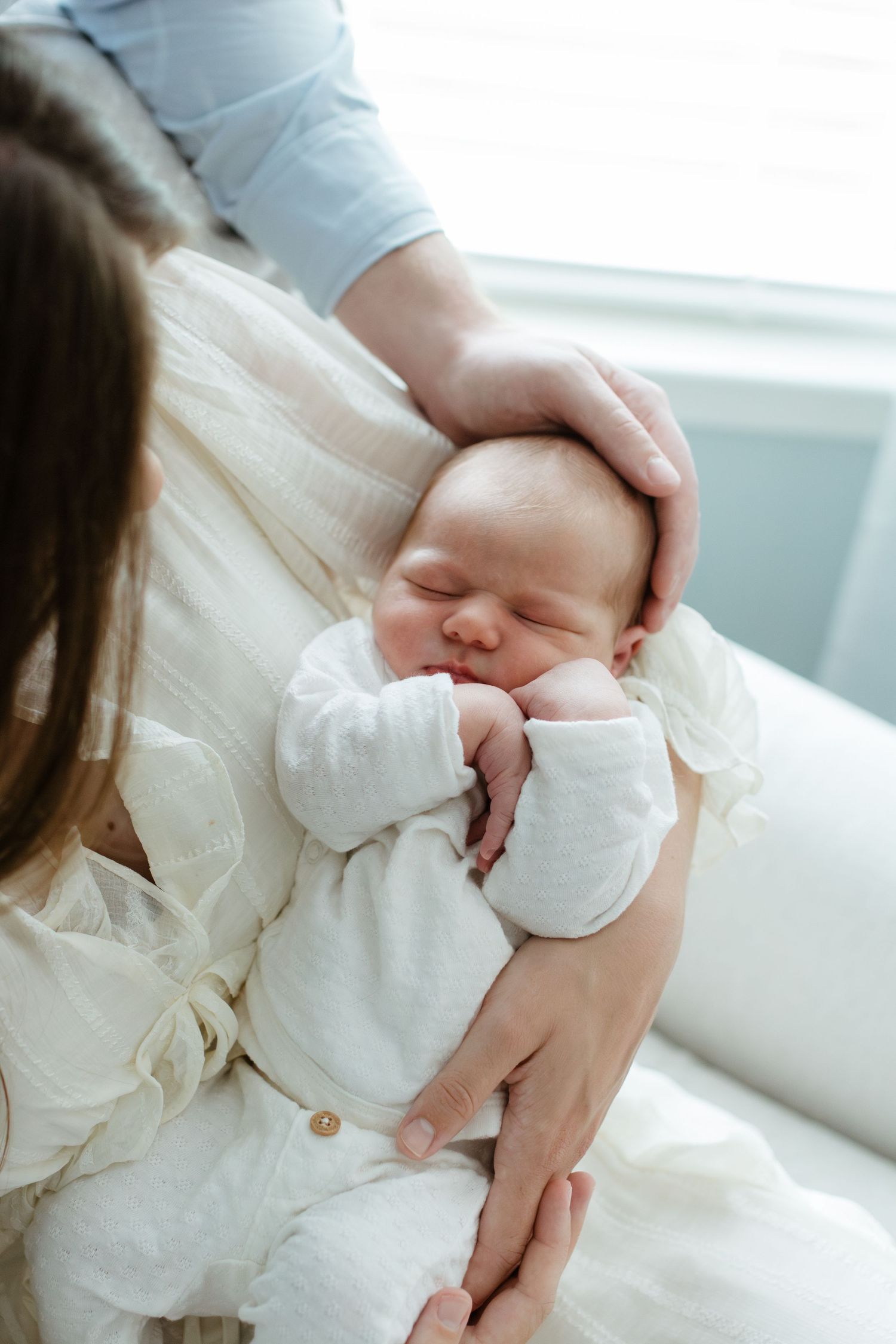 sleepy newborn being held in his mother's arms during an in-home newborn photoshoot in charlotte nc