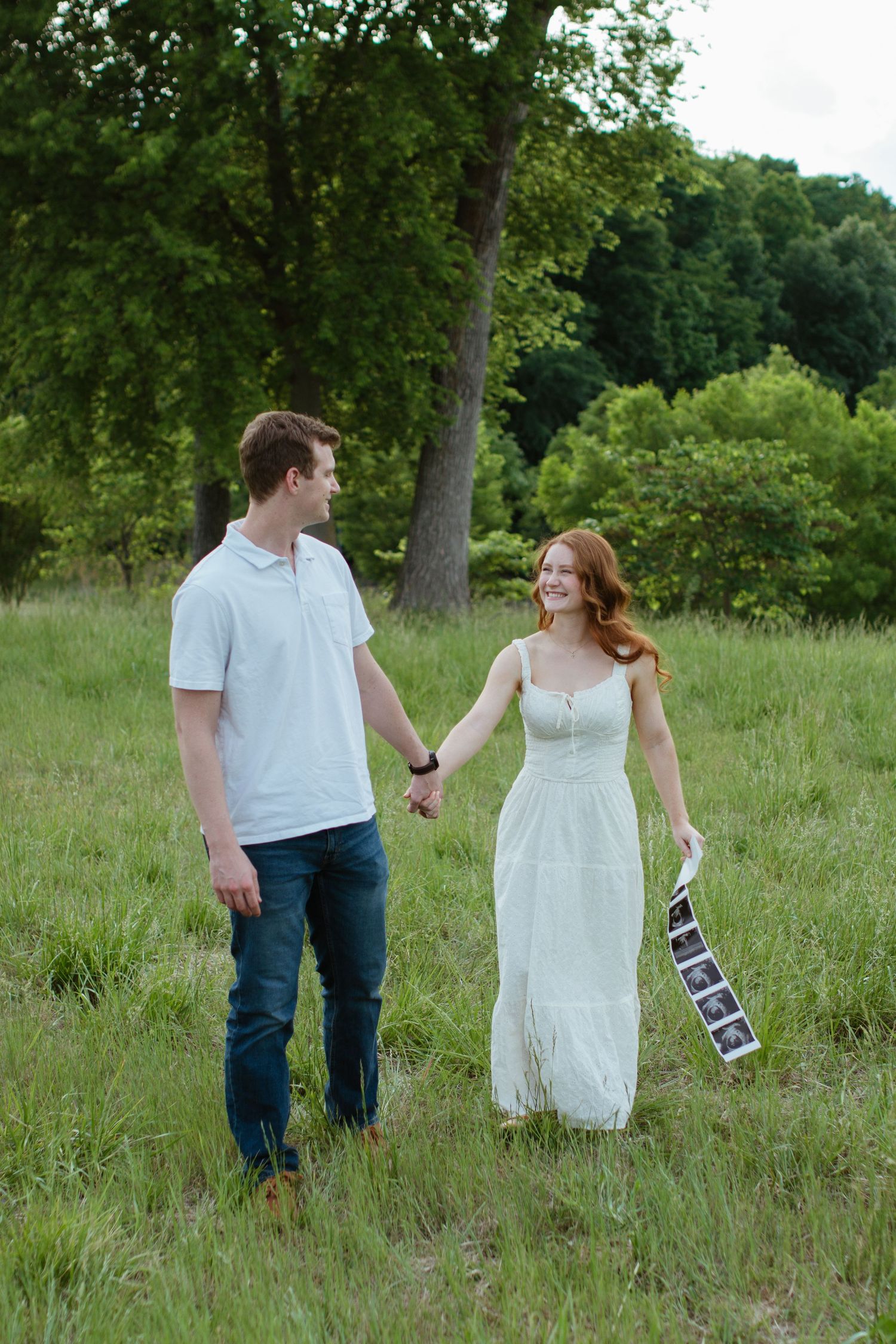 Couple walking together in a field for a dreamy pregnancy announcement session in rock hill