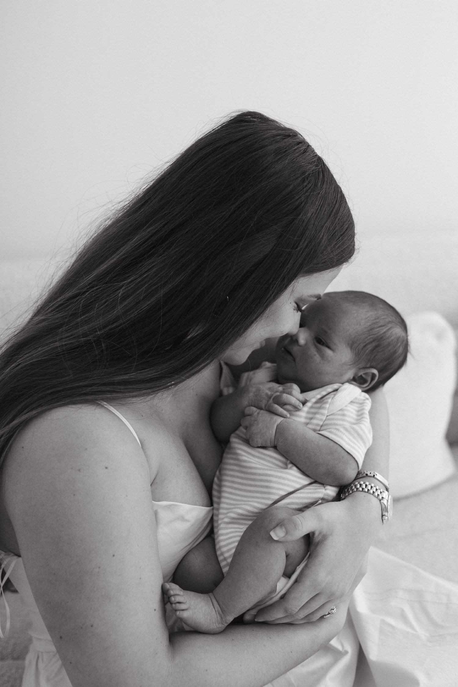 Mother holding newborn baby close during early bonding moment