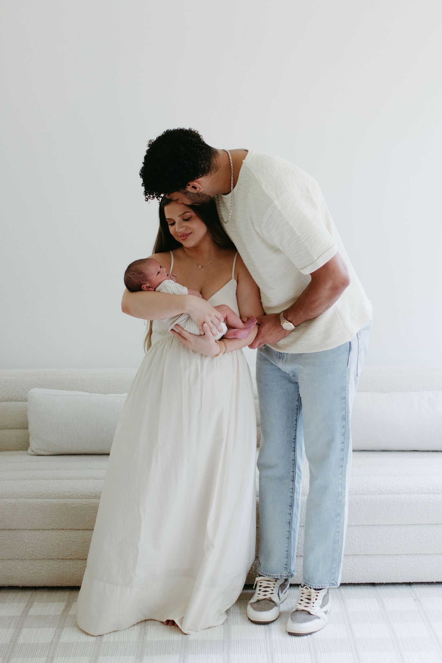 couple posing holding their newborn baby for an in-home charlotte newborn photoshoot