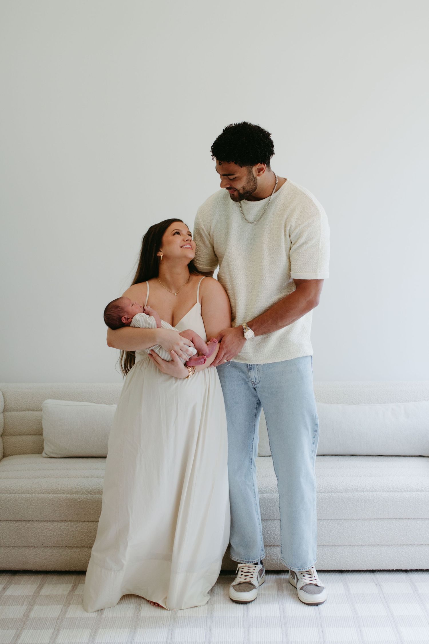 Newborn baby nestled in mother's arms next to father during an in-home lifestyle session in rock hill