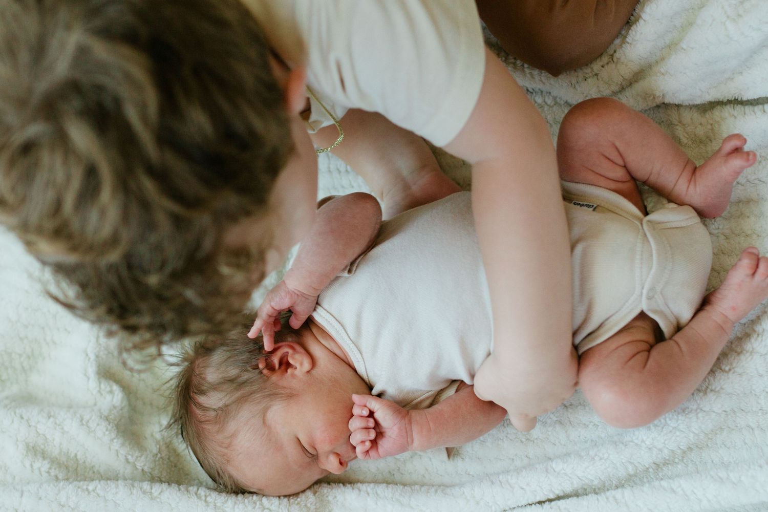 Older brother gently touching his newborn baby brother during a lifestyle session