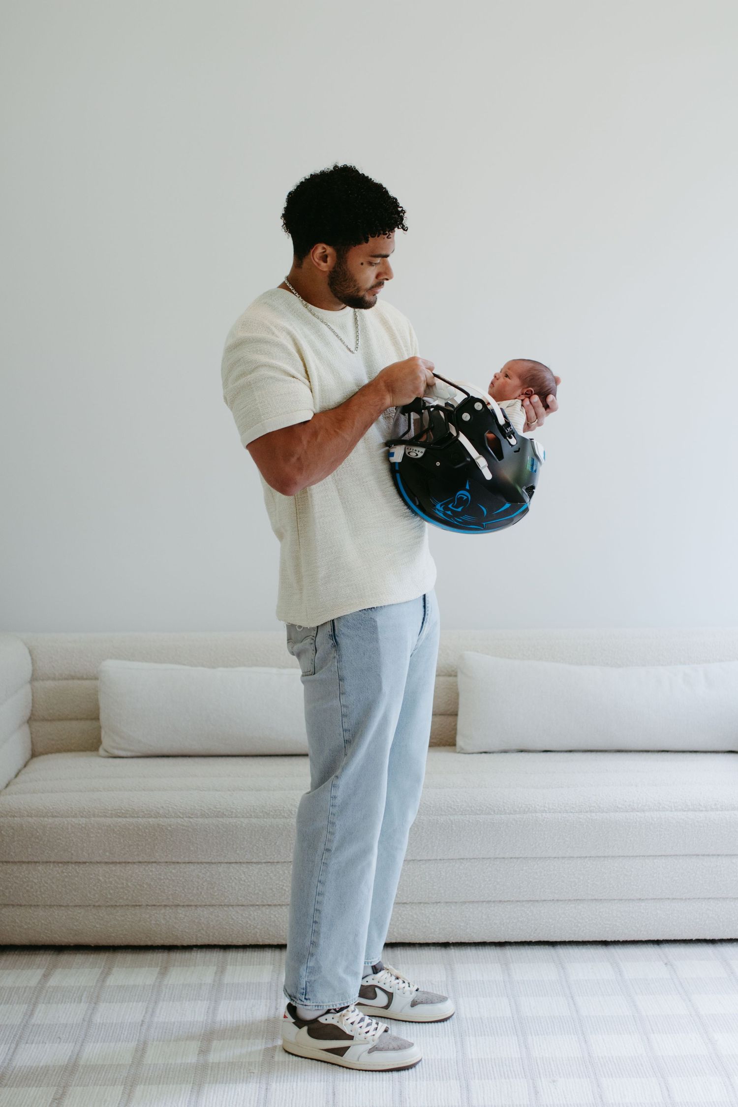 NFL player from the Carolina Panthers cradling his newborn in a candid family moment