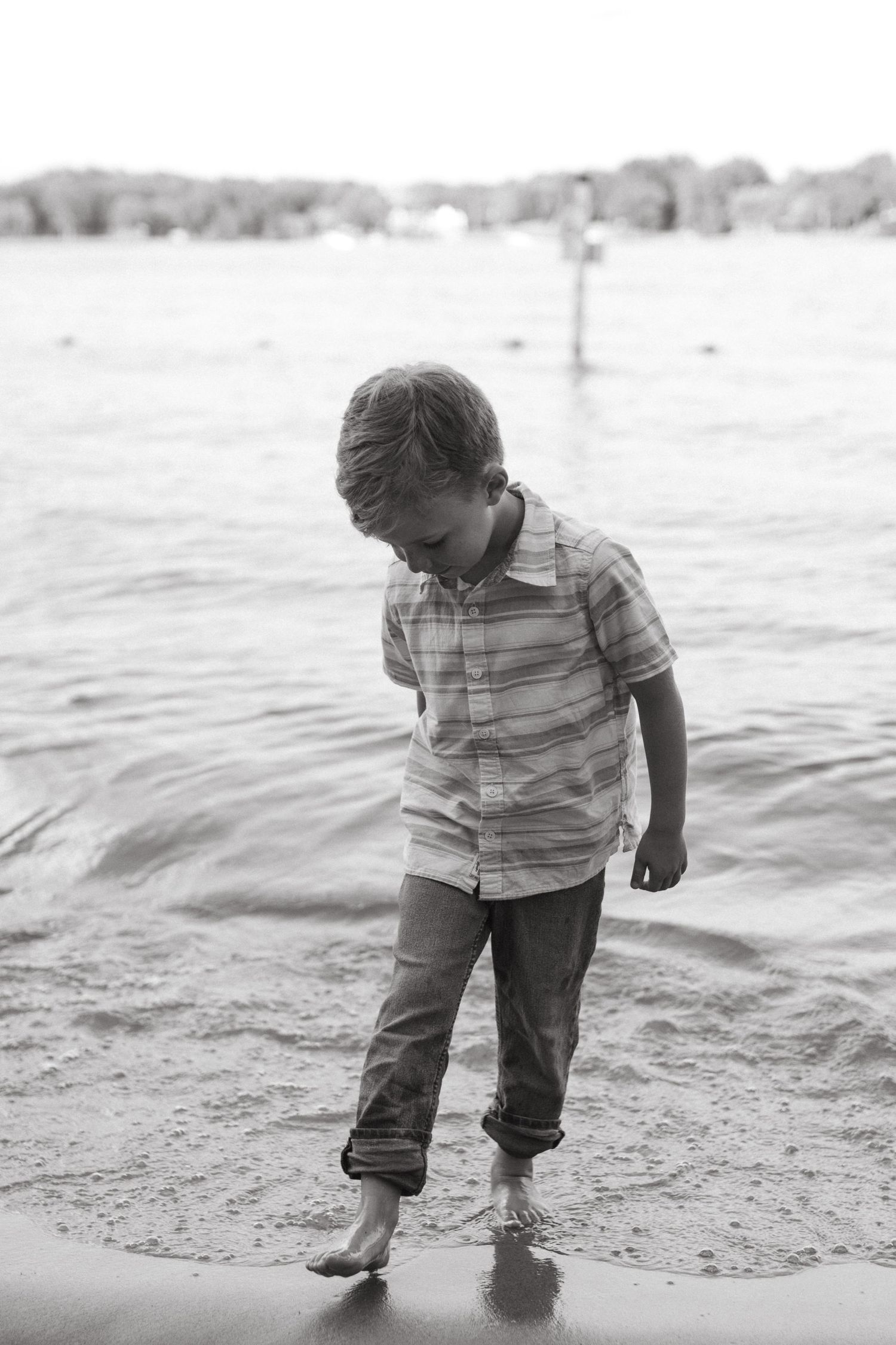 little boy walking along the lake shore