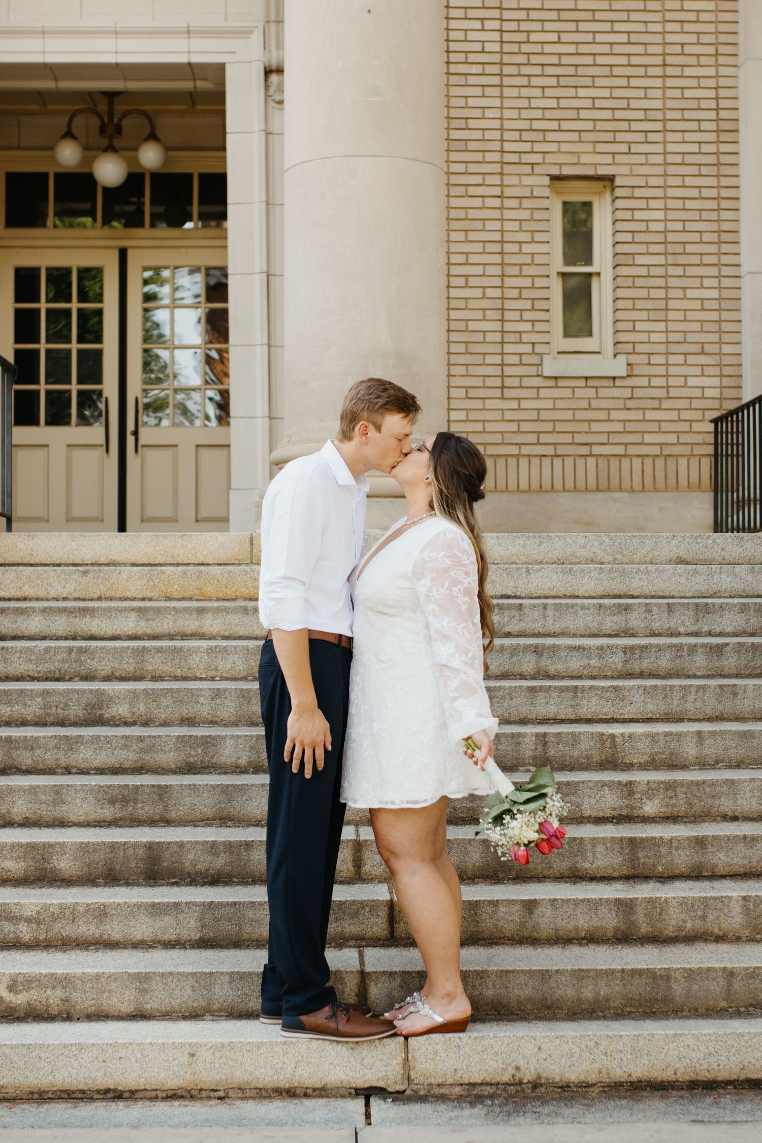 Bride and groom kissing on the courthouse steps during their wedding