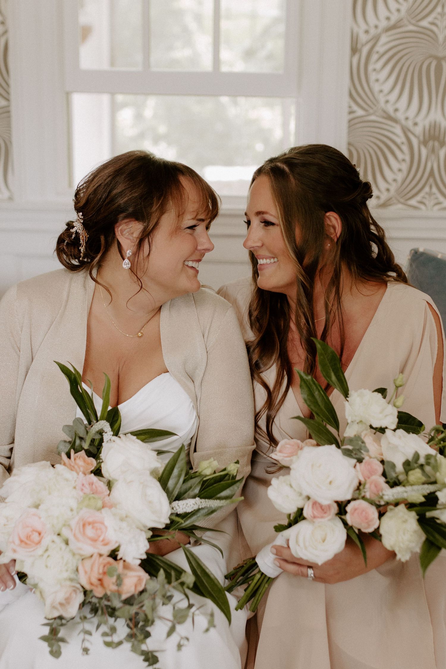 Candid moment of bride and maid of honor laughing together