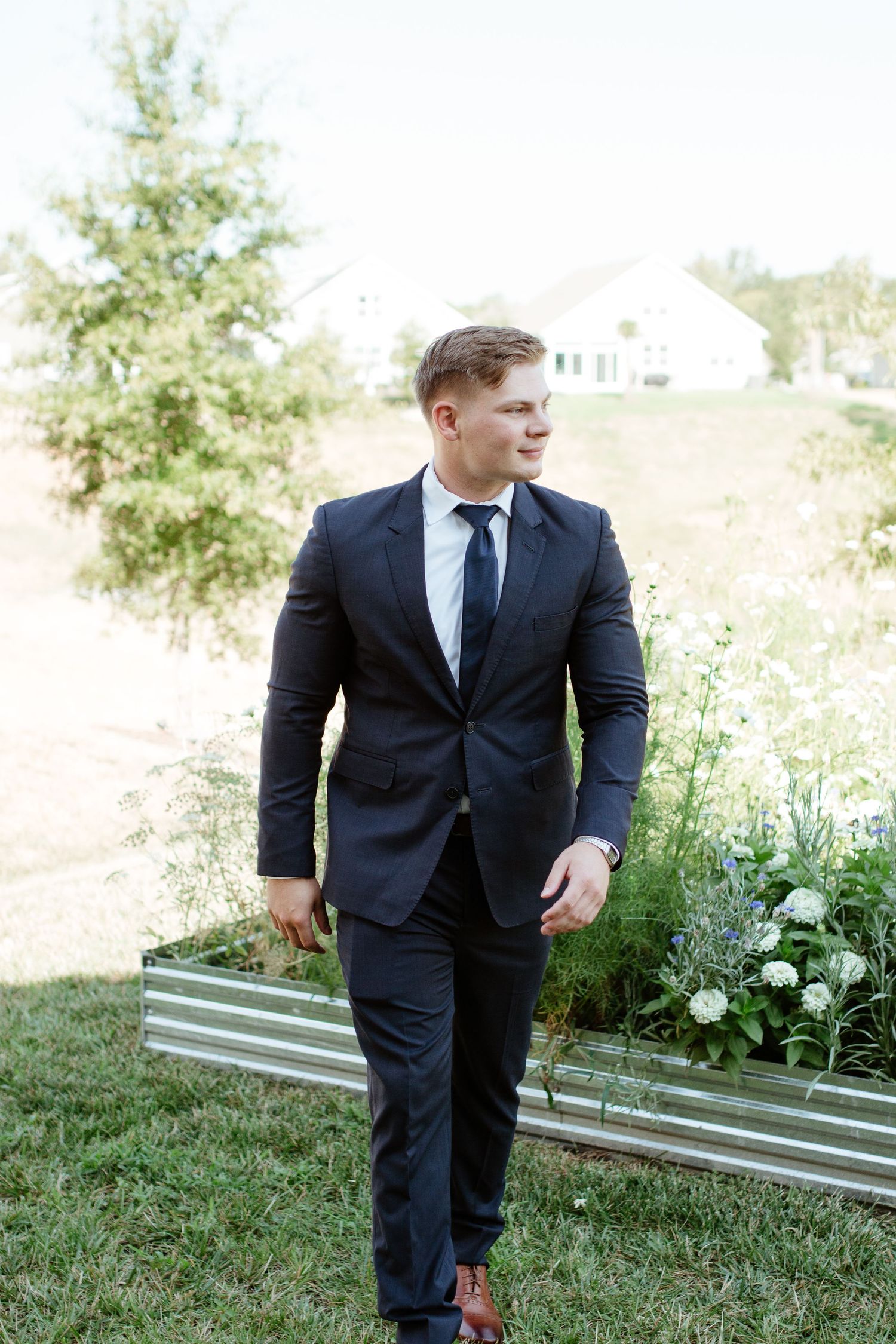 Groom standing outdoors in his wedding suit