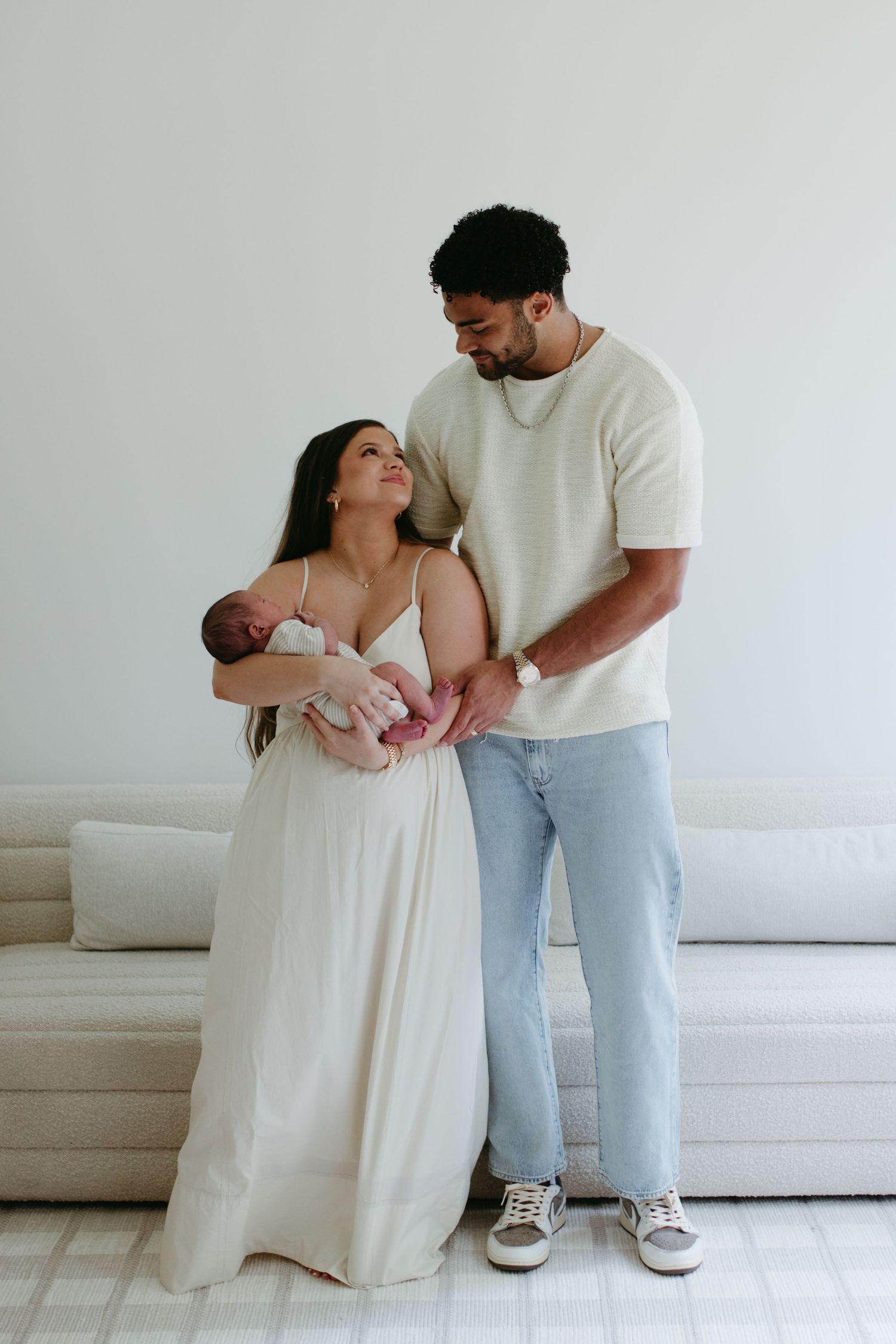 parents holding newborn baby standing next to couch in rock hill sc