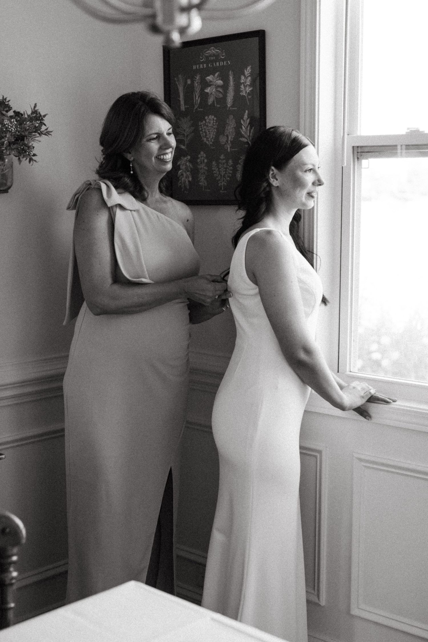 Mother zipping up bride’s wedding dress before the ceremony