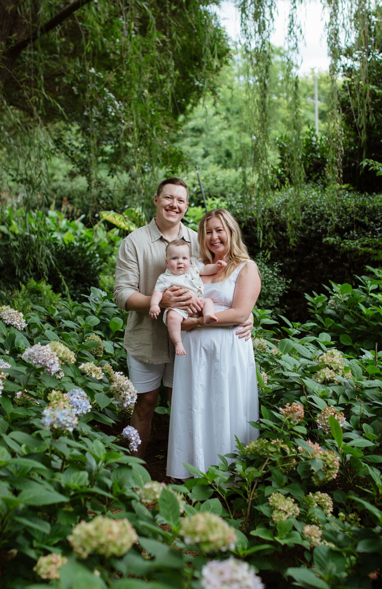 couple posing together with their baby for a family photoshoot in McGill Rose Garden in Charlotte nc