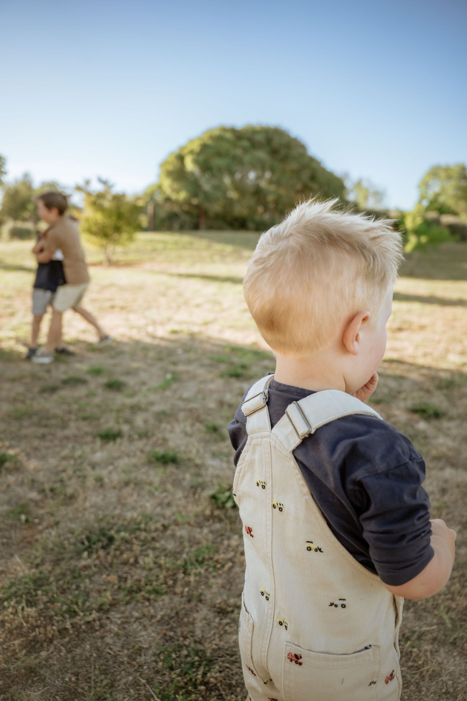 Small boy watching brothers play