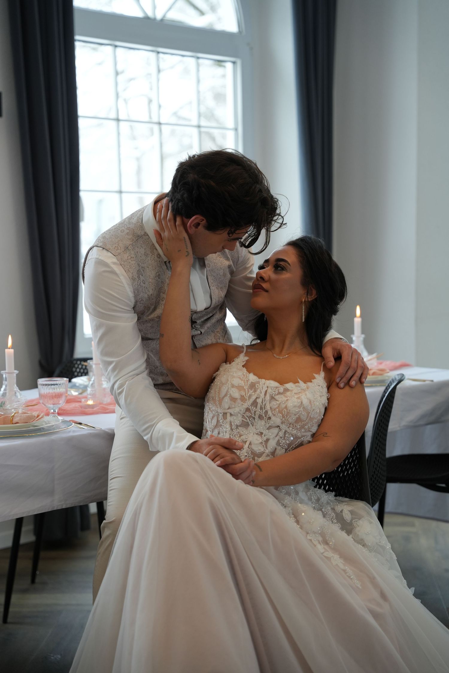 An intimate moment between newlyweds at their reception table with candlelight.