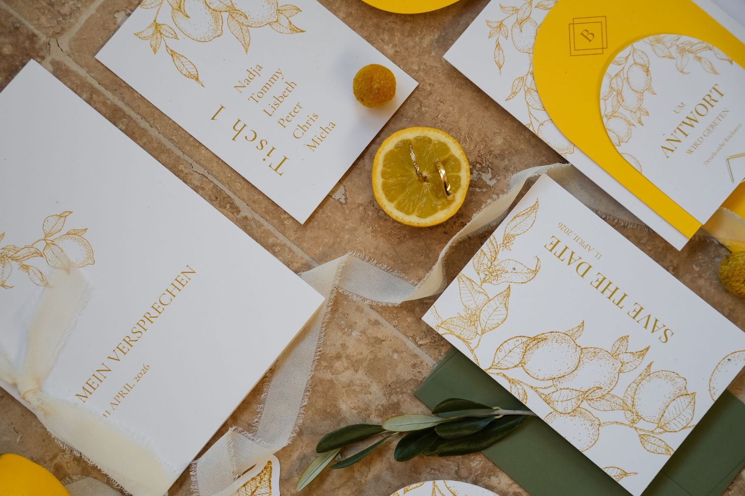 Elegant gold foil wedding stationery with lemon motifs, including save the date cards and vows booklet.