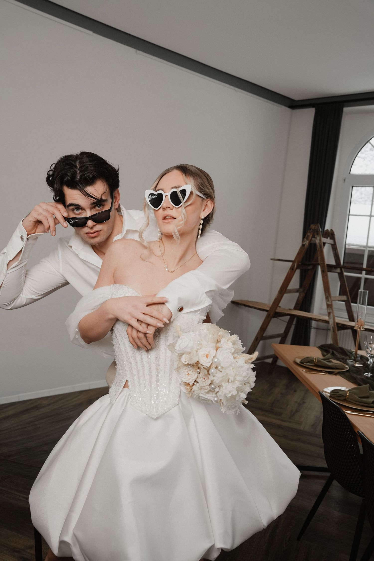 Playful wedding couple wearing sunglasses and posing in a casual moment.