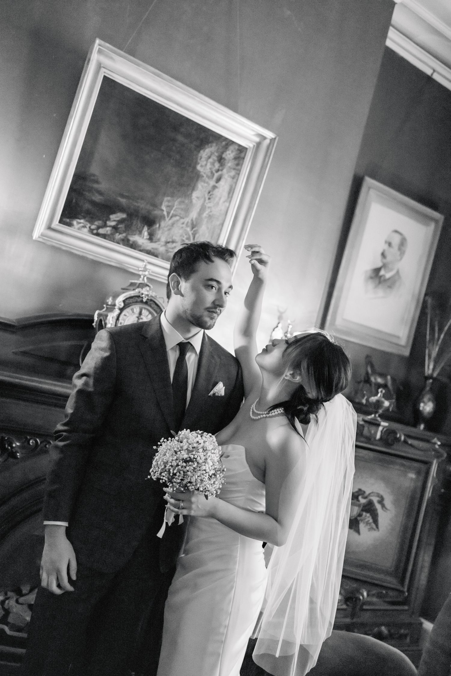 Vintage-style wedding portrait of couple in elegant attire with baby's breath bouquet.