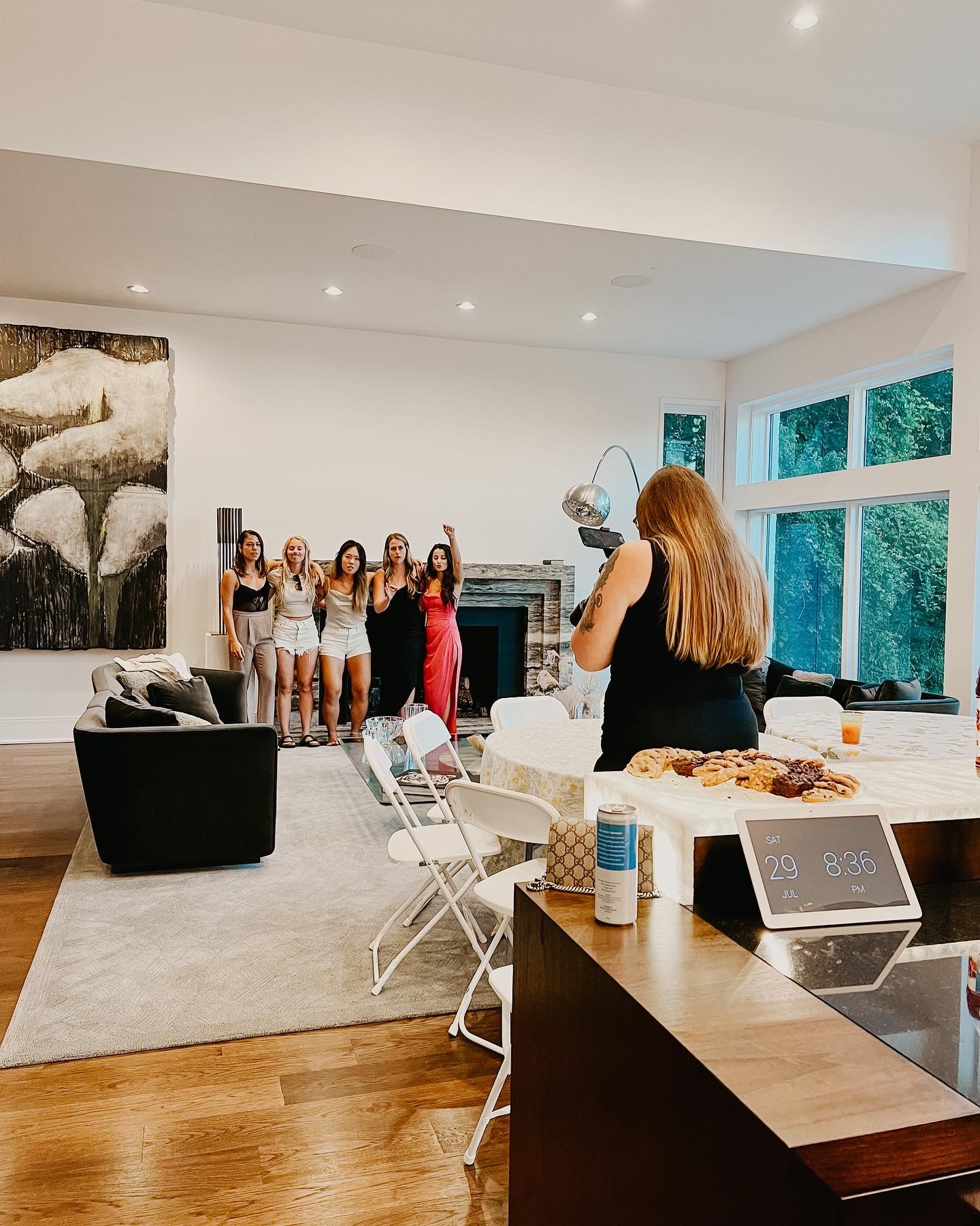 Photographer capturing group of women in lingerie during boudoir party session in modern home.
