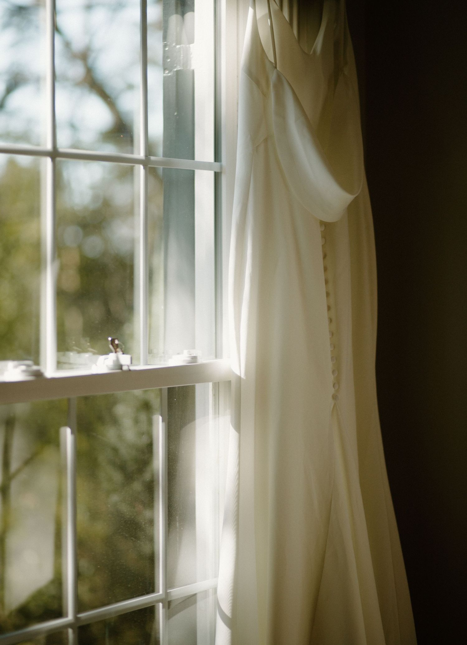 Sunlight streams through a window pane beside flowing white curtains in a serene, light-filled room.