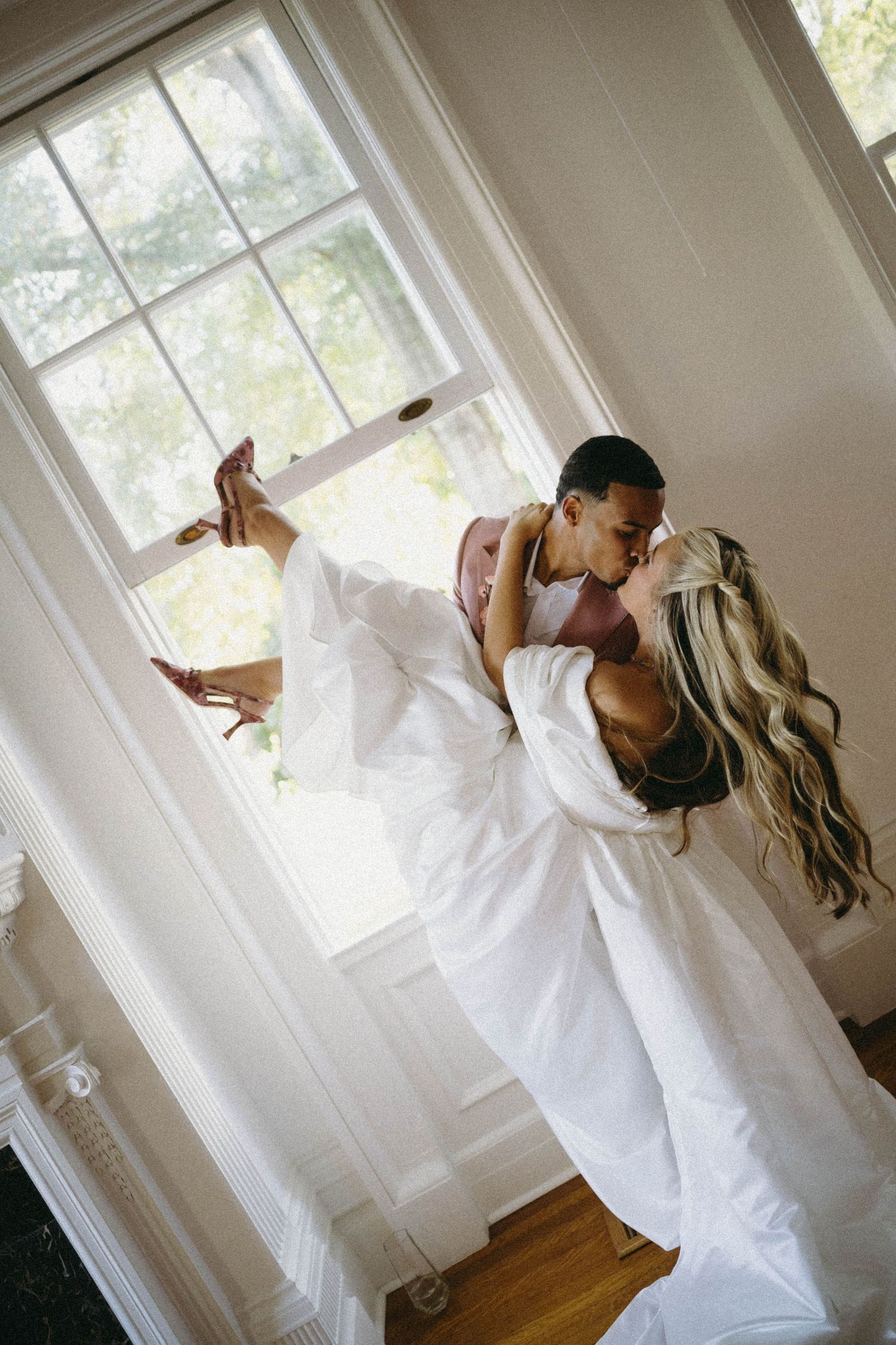 Series of romantic wedding photos showing couple in white dip dancing near bright windows.