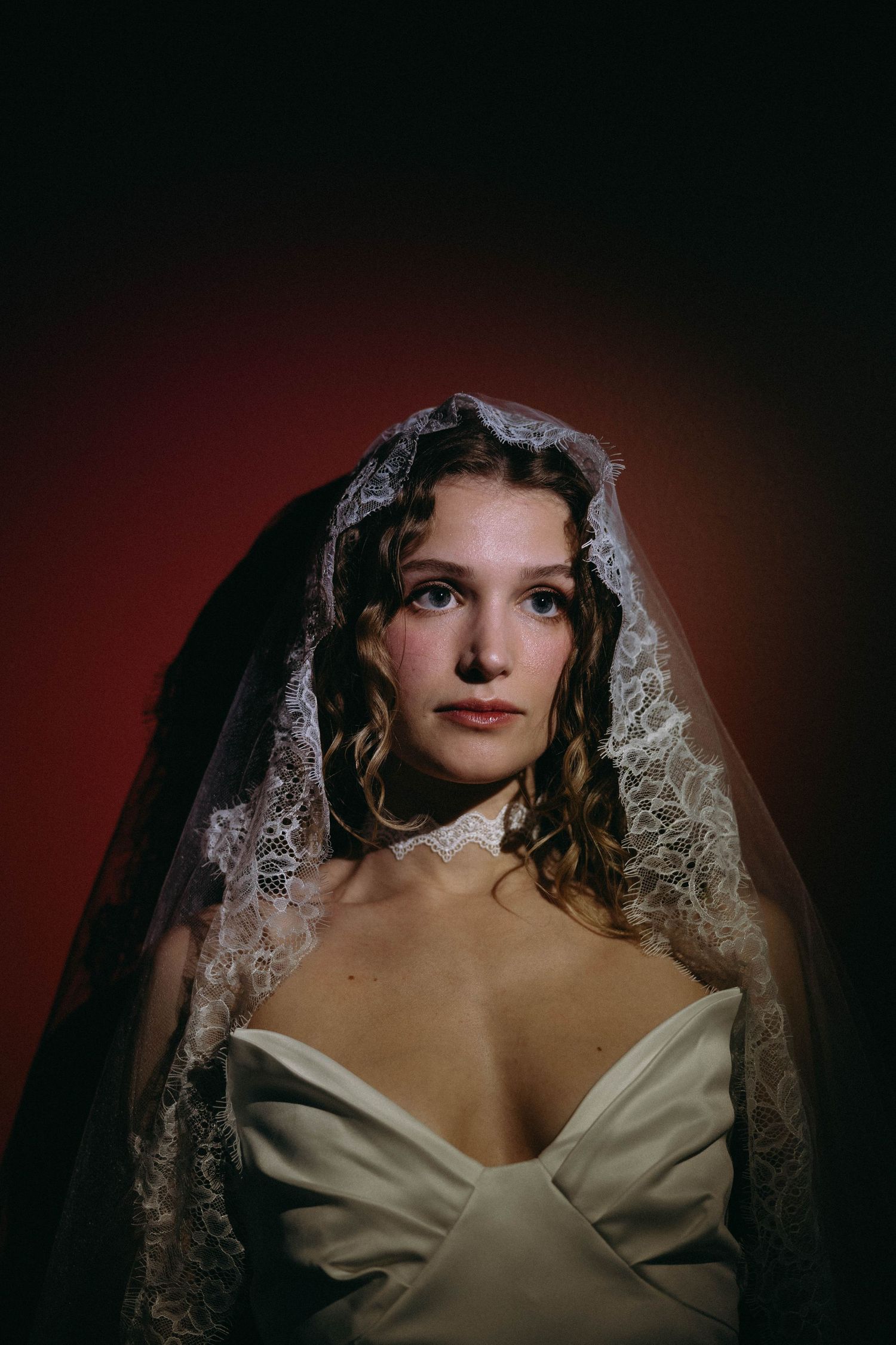 A dramatic portrait series showing a figure in a white bridal gown and delicate lace veil against a dark red background.