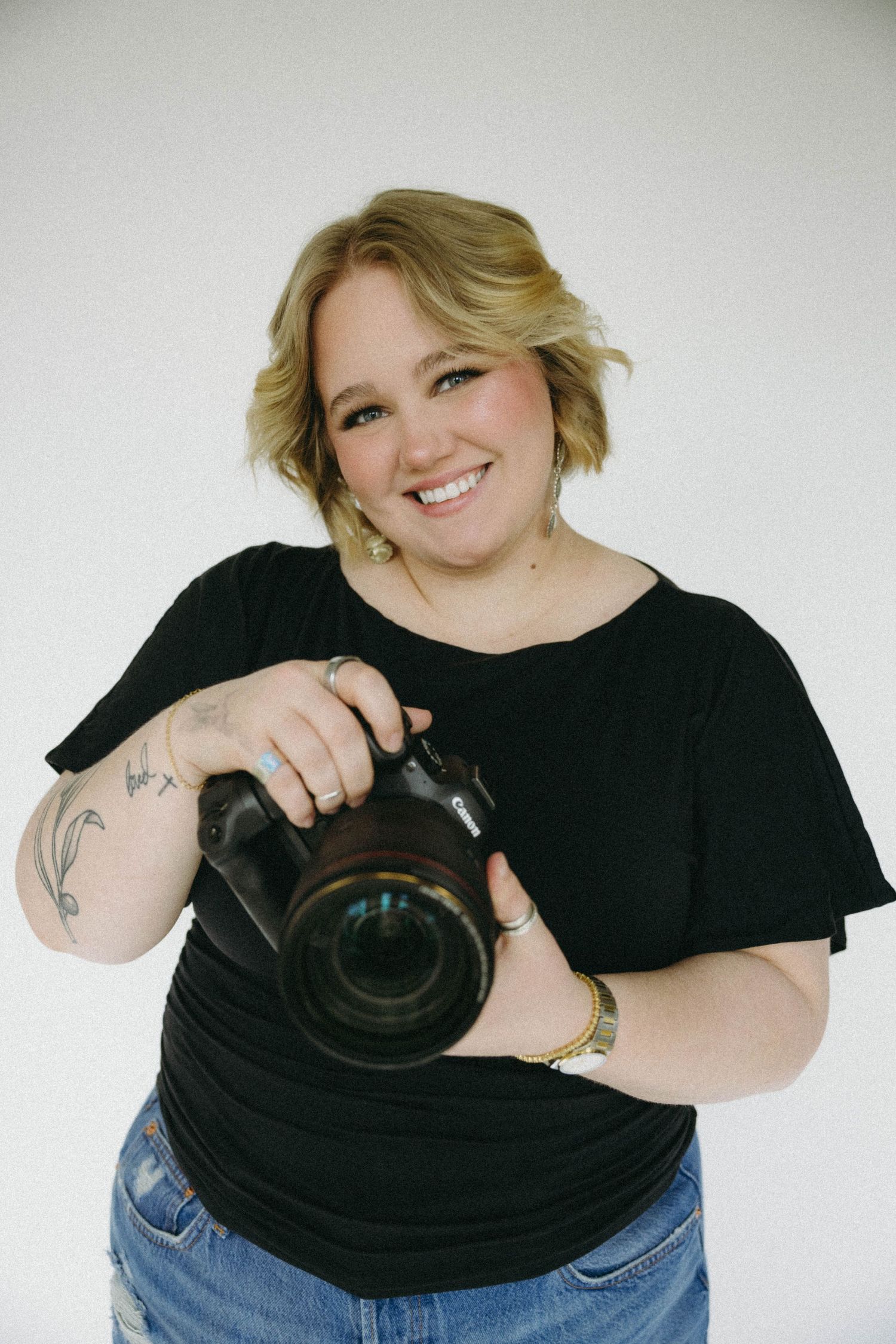 A person in a black shirt holds up a vinyl record while making playful poses against a white background.