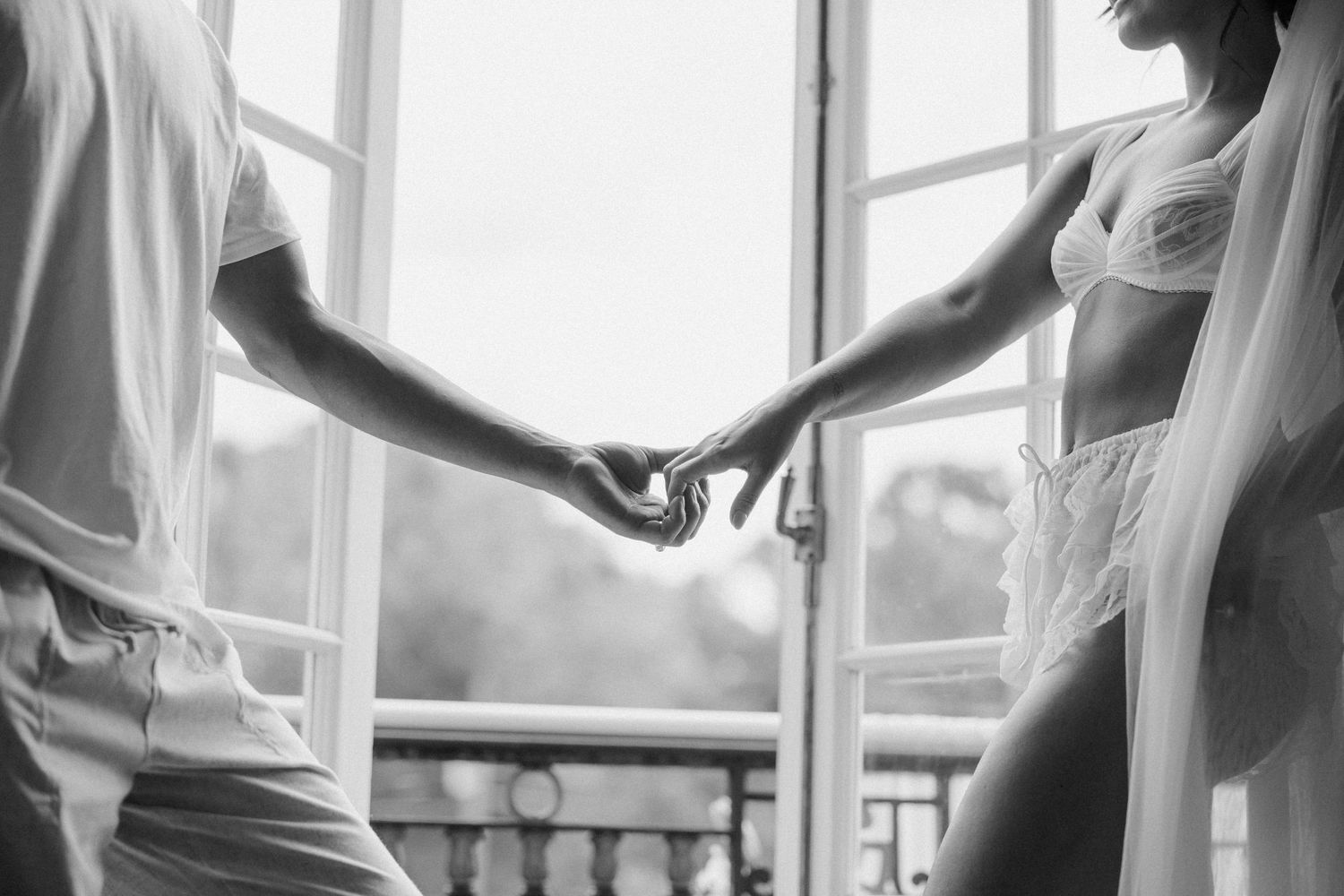 A group of dancers practicing ballet moves at a studio with natural light streaming through large windows.