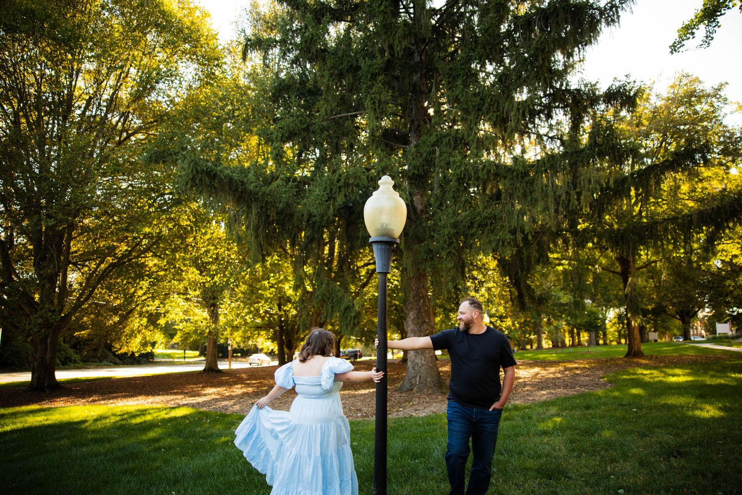Golden sunlight filters through trees in a romantic outdoor wedding setting with a natural pathway.