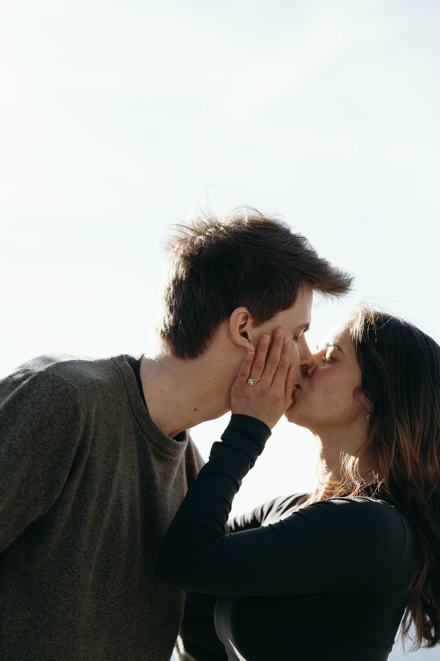A romantic silhouetted couple shares a tender kiss against a bright white background.