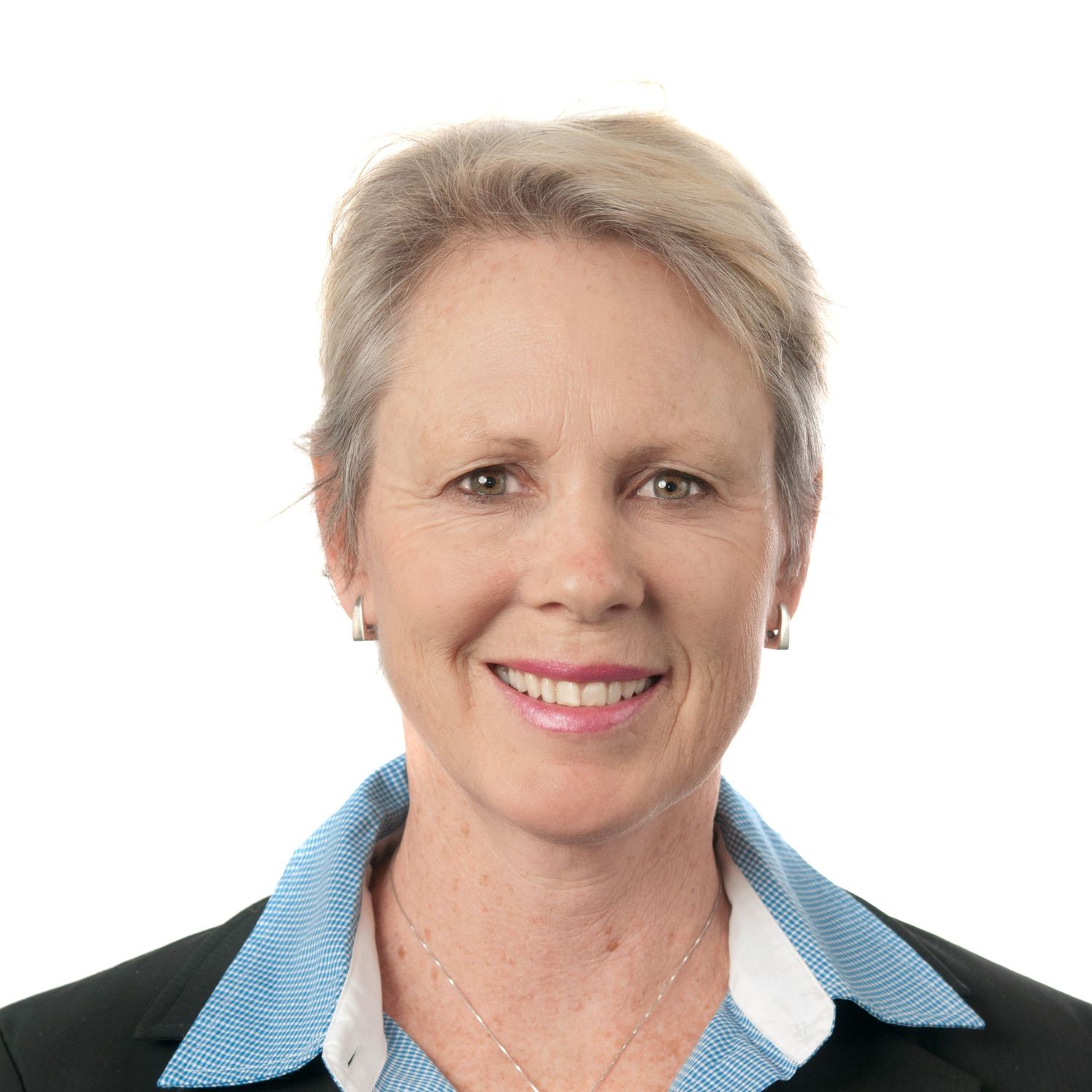 Professional headshot of a smiling middle-aged woman with short gray hair wearing a blue collared shirt and black blazer.
